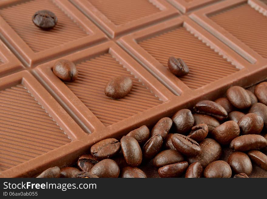 Coffee grains are on the bar of chocolate. Coffee grains are on the bar of chocolate