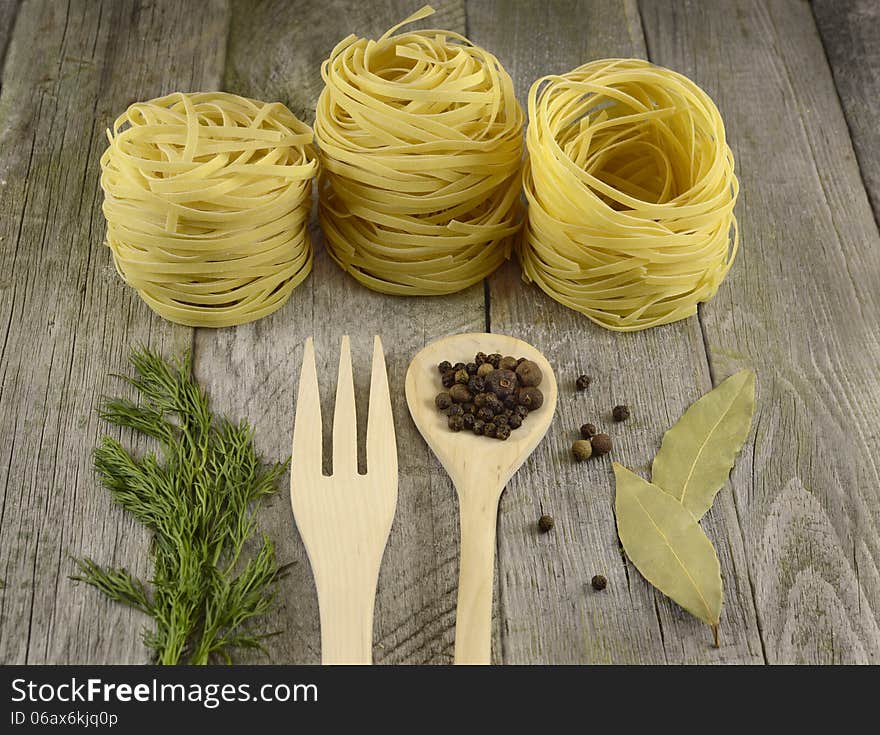 Rolled noodles with wooden spoon and fork on the wooden table. Rolled noodles with wooden spoon and fork on the wooden table