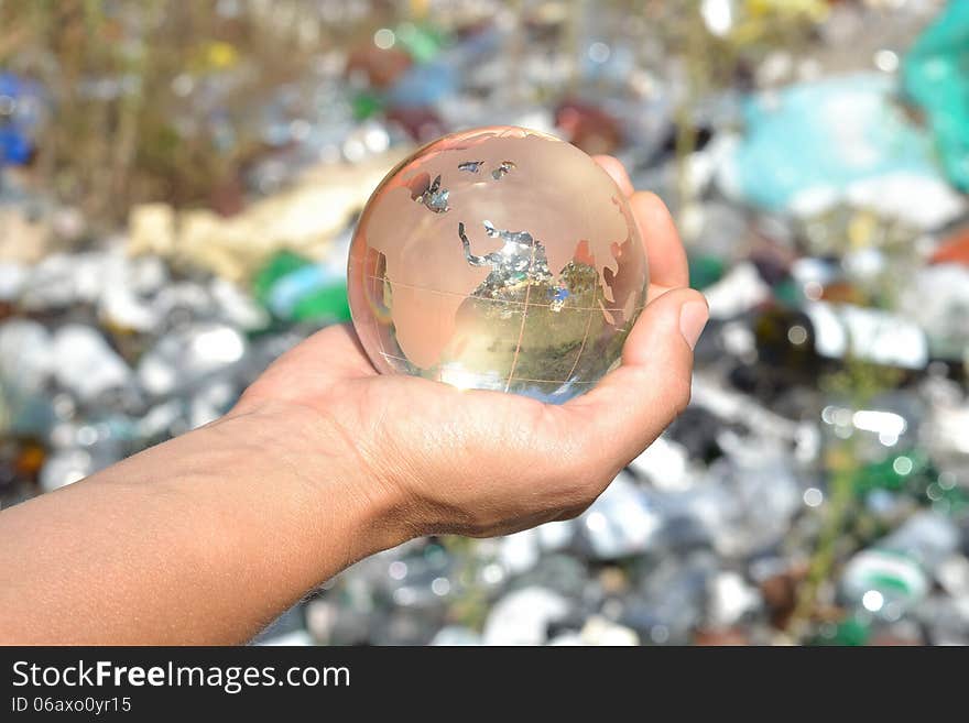 Globe in hands on garbage background.