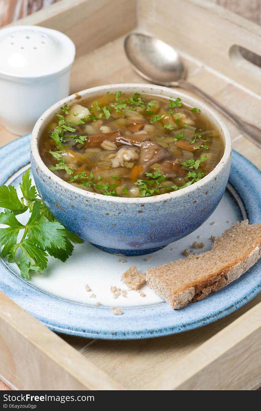 Bowl of mushroom soup with pearl barley on a wooden tray