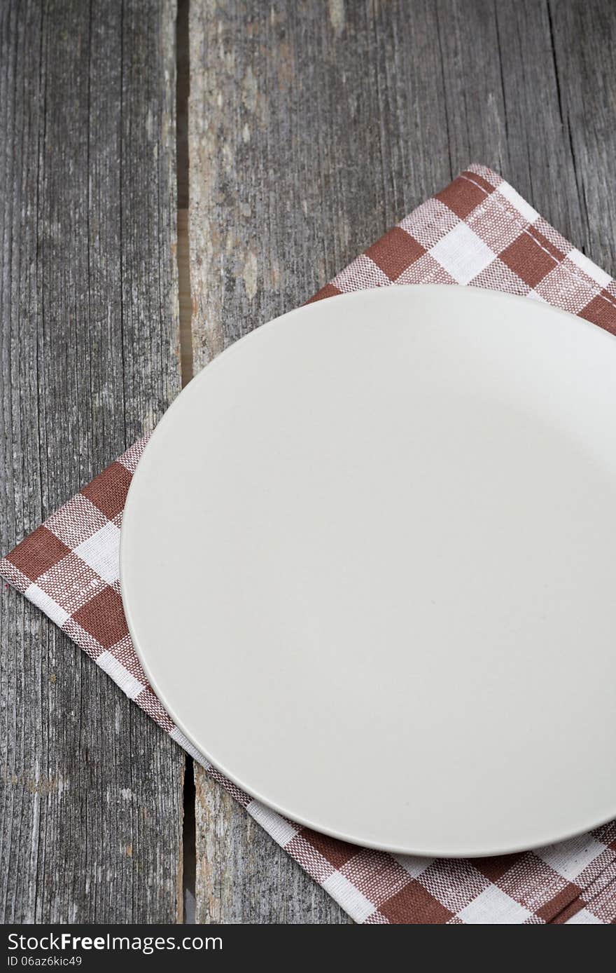 Empty plate on a napkin on wooden table, concept