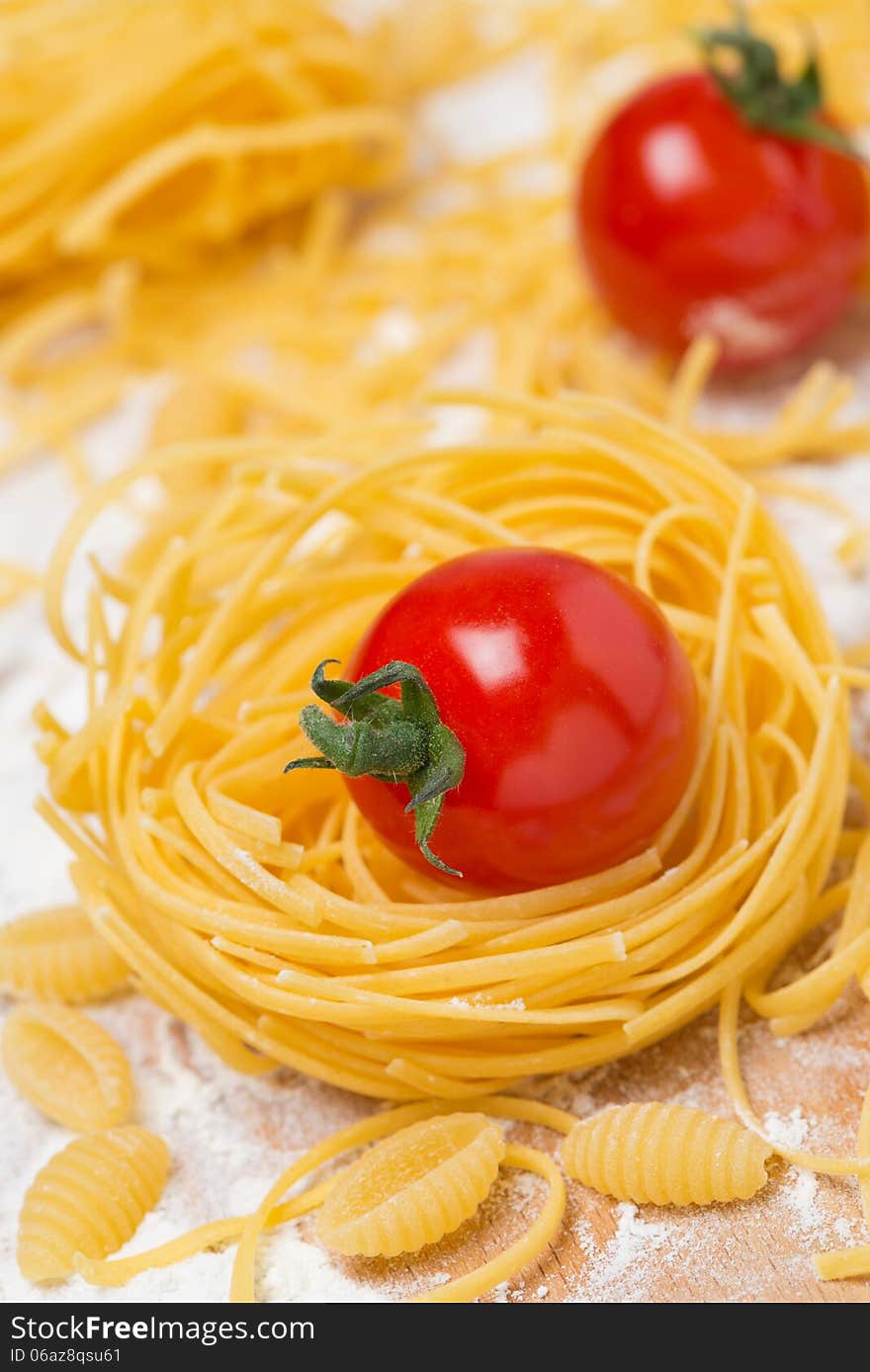 Italian egg pasta nest, cherry tomatoes on a cutting board, selective focus, vertical