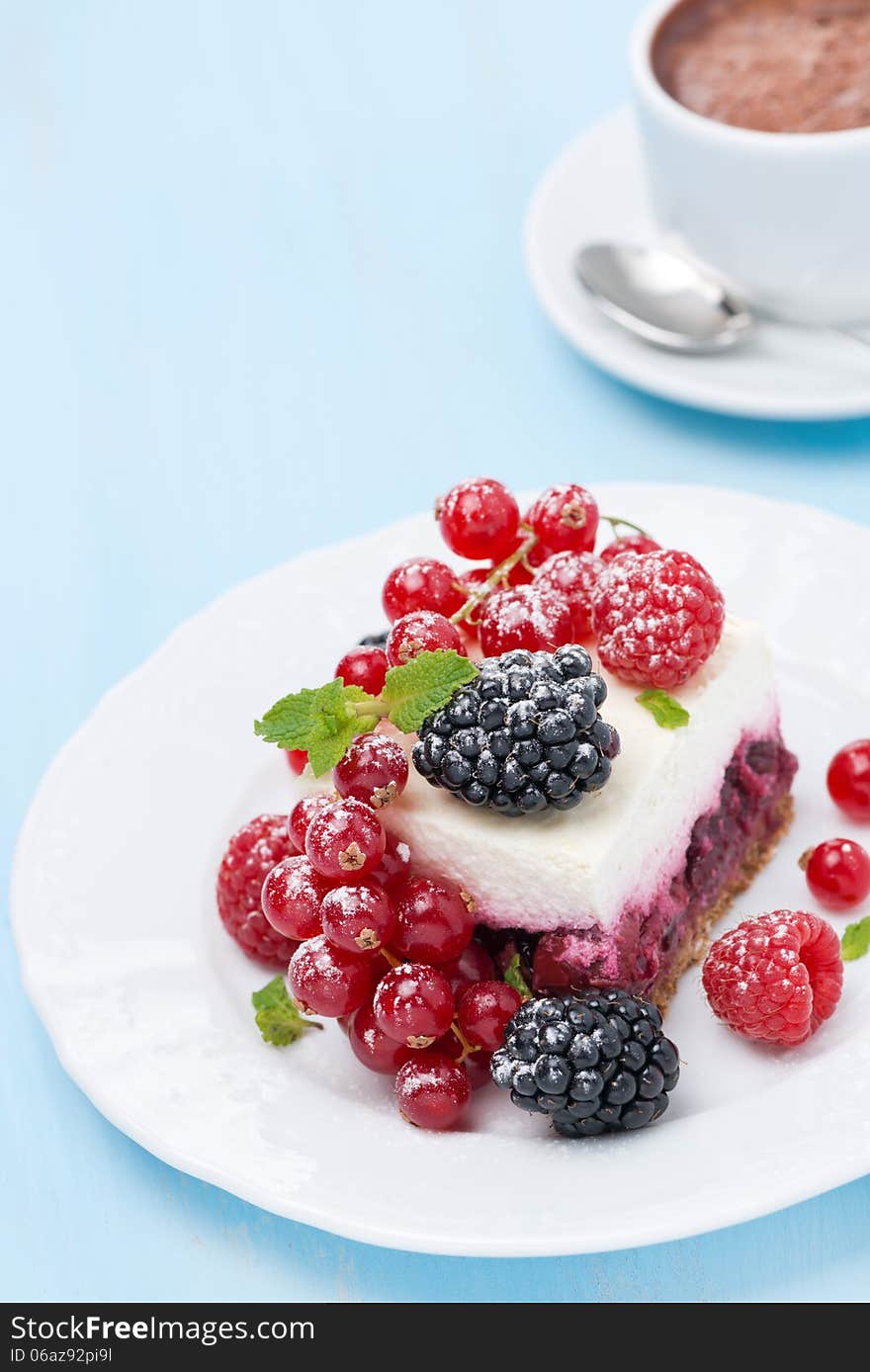 Piece of cake with fresh berries and coffee on blue background