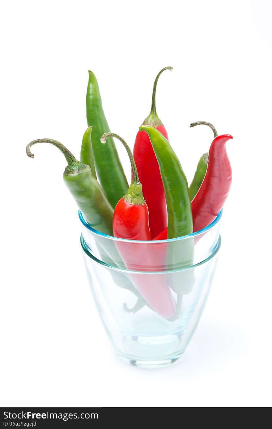 Red and green chili peppers in a glass, isolated on white