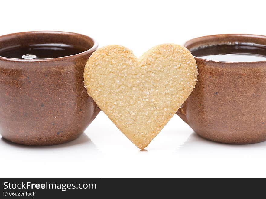 Two cups of coffee and cookies in the shape of hearts