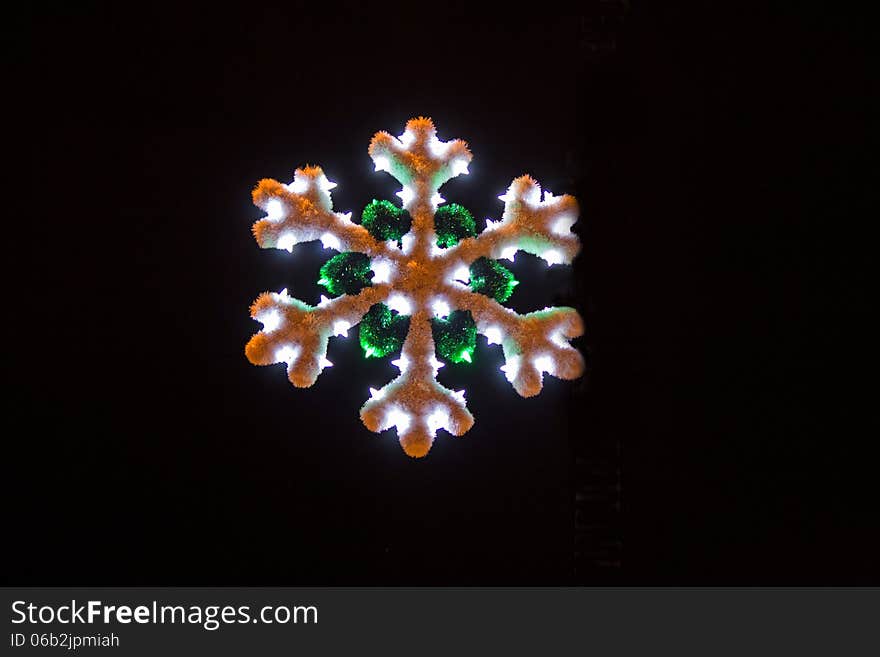 Lit white and green Christmas snowflake on a black background. Lit white and green Christmas snowflake on a black background