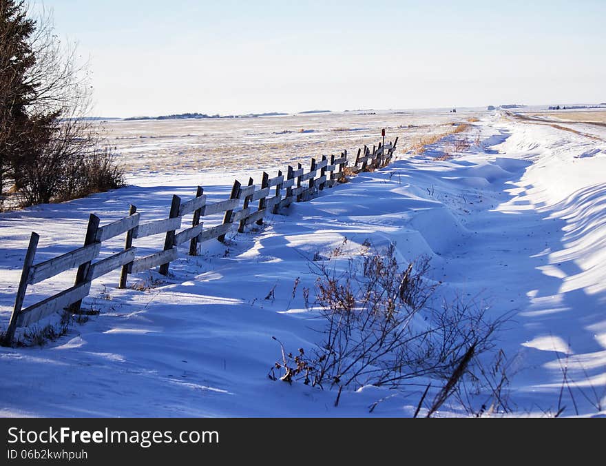 Wood fence along a ditch with snow drifts. Wood fence along a ditch with snow drifts