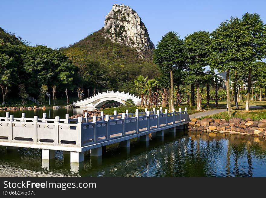 Chinese garden landscape:winding corridor,stone arch bridge and hill.