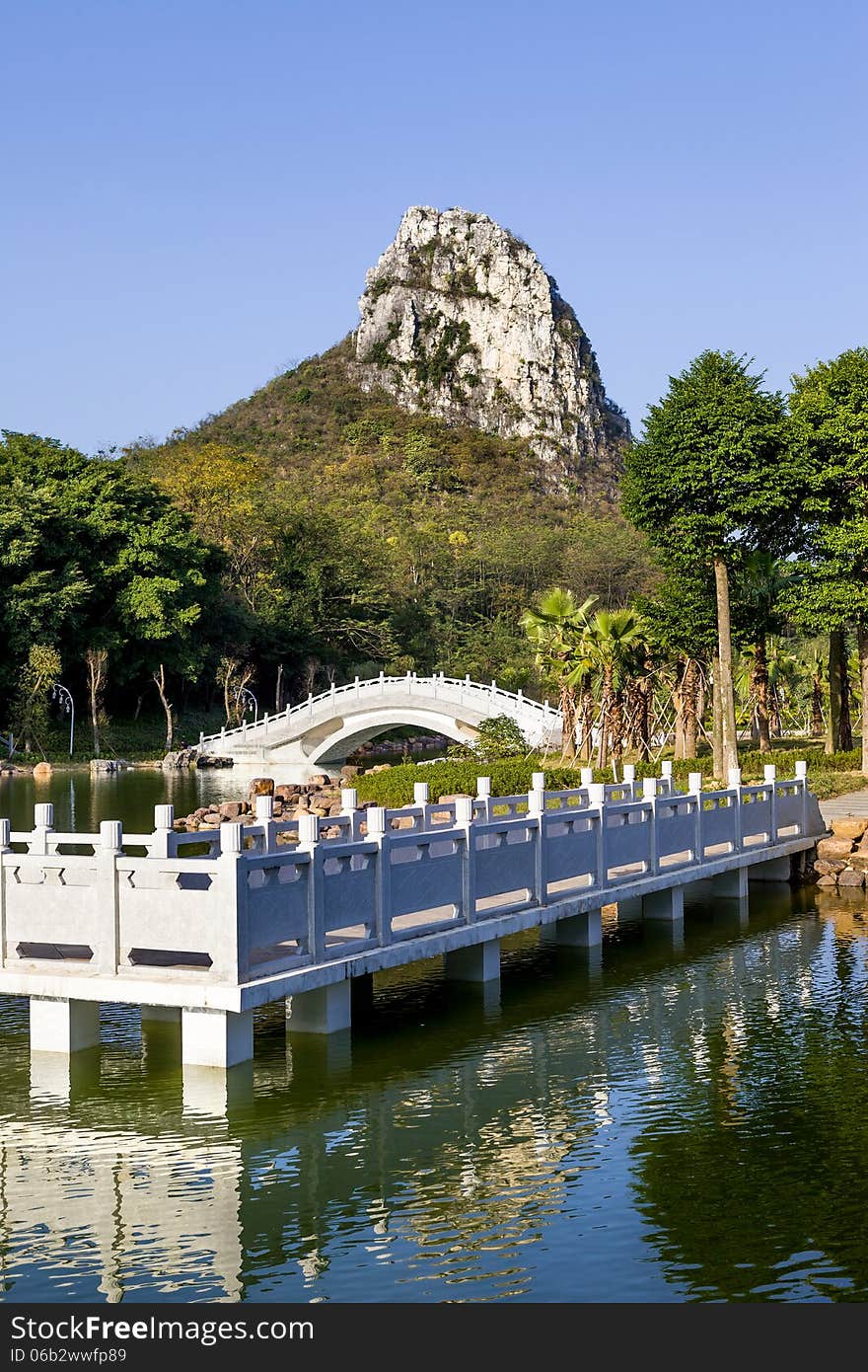 Chinese garden landscape:winding corridor,stone arch bridge and hill.