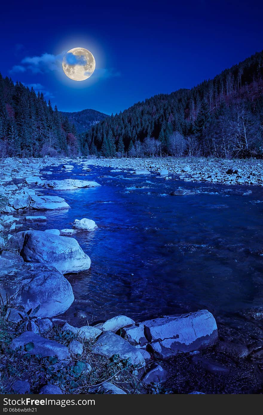 River flows by rocky shore near the autumn mountain forest at night. River flows by rocky shore near the autumn mountain forest at night