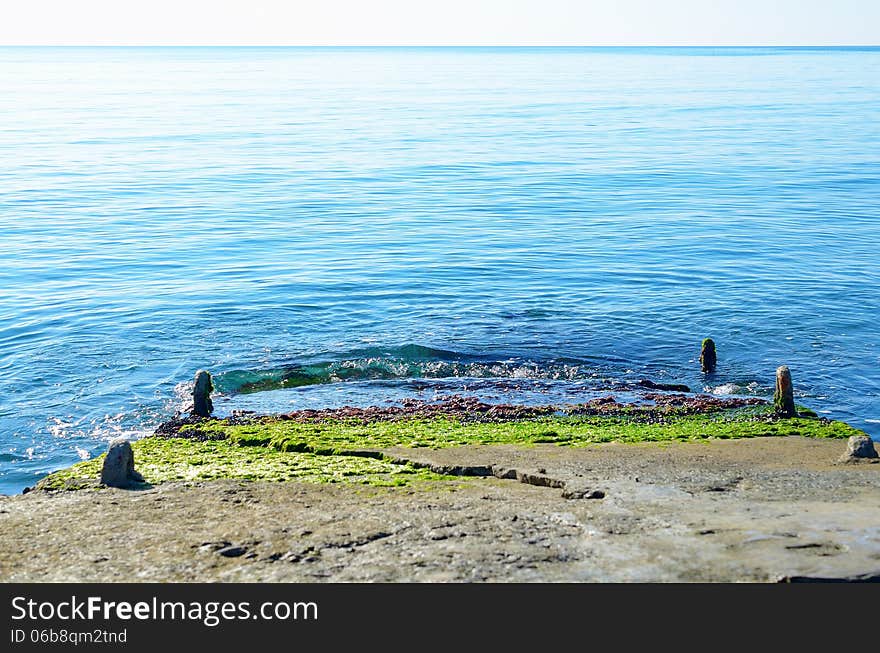 Stone jetty with green algae, stretching into the sea. Stone jetty with green algae, stretching into the sea