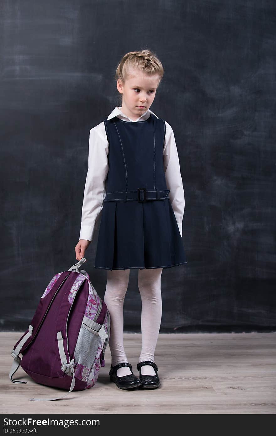 Latecomers little schoolgirl with backpack near blackboard. Latecomers little schoolgirl with backpack near blackboard