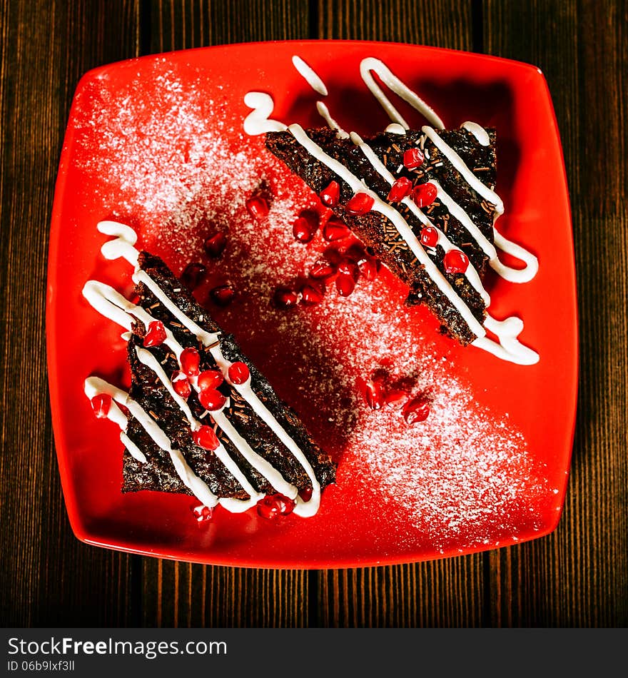 Christmas chocolate cake dessert with pomegranate grains on red plate. Christmas chocolate cake dessert with pomegranate grains on red plate