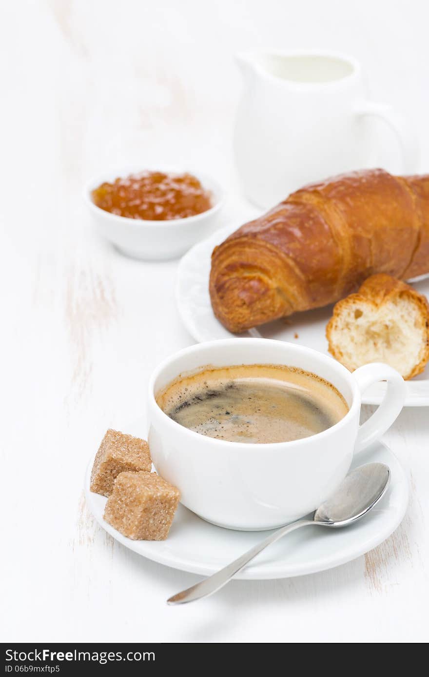 Cup of black coffee and croissants with orange jam