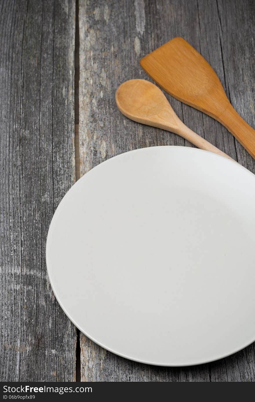 Empty plate, wooden spatula and spoon, concept