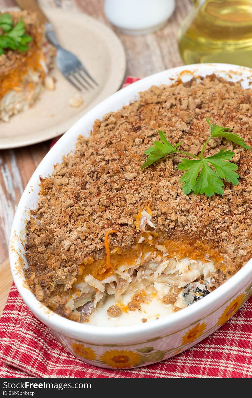 Gratin with fish and pumpkin in a ceramic form, close-up, vertical, top view