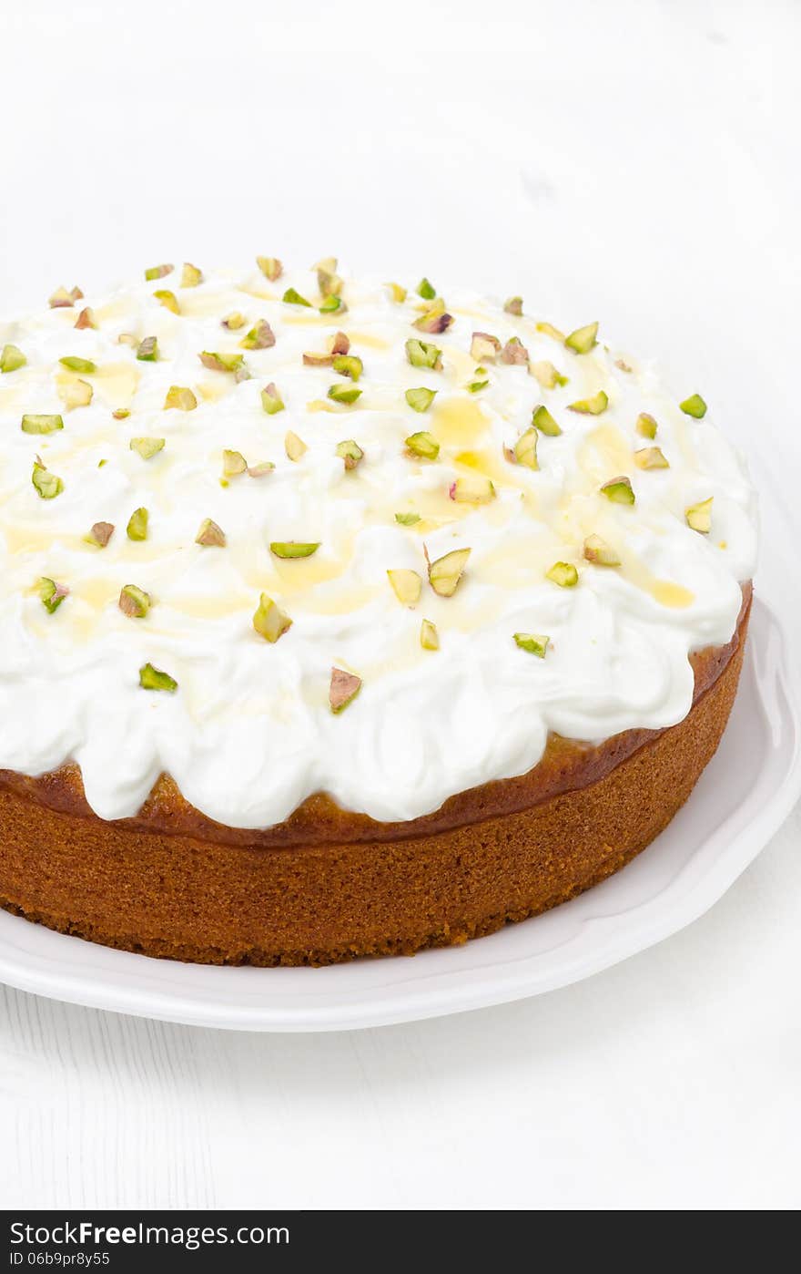 Orange cake with Greek yogurt, honey and pistachios on a plate, close-up