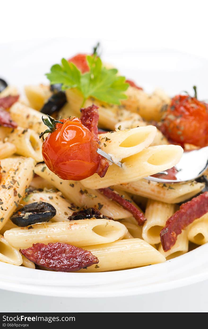 Penne pasta with sausage, cherry tomatoes and olives, close-up