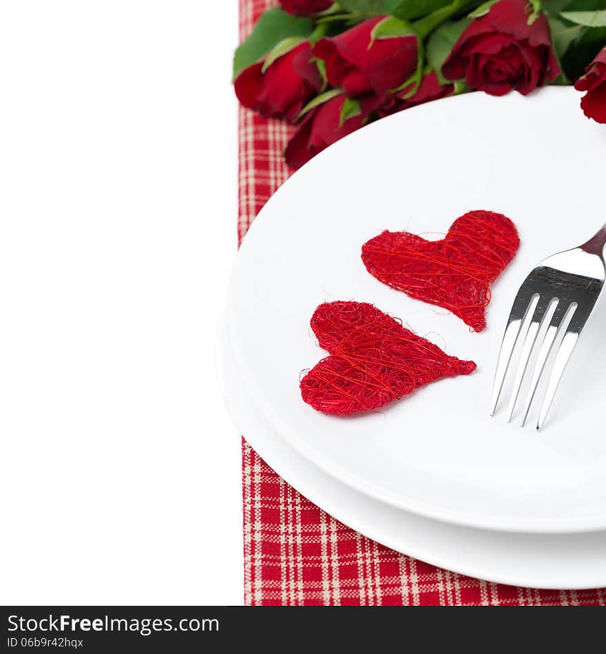 Two wicker heart on a plate and red roses, isolated on white