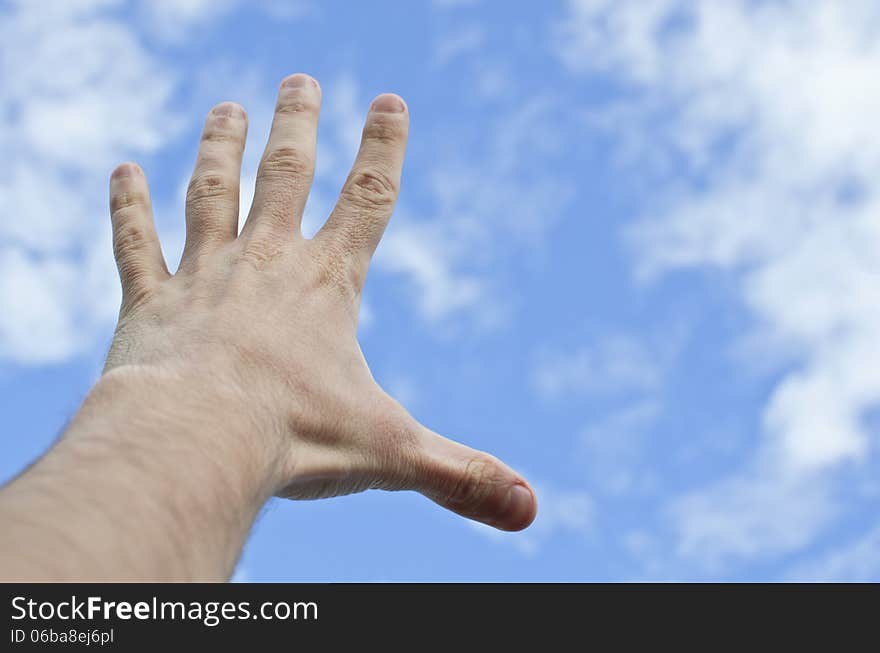 Hand stretched to the blue cloudy sky. Hand stretched to the blue cloudy sky