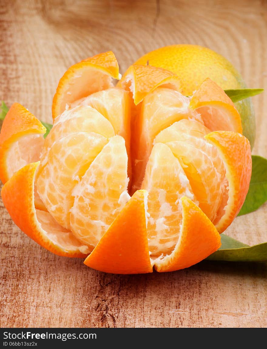 Fresh Ripe Tangerine with Segments and Citrus Peel closeup on Wooden background