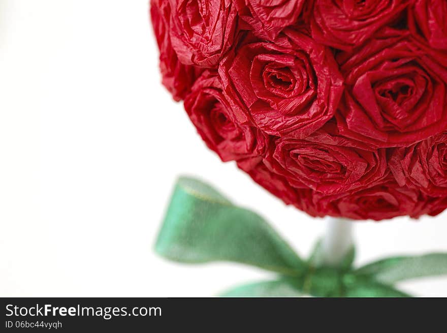 Close-up of red crepe paper rose topiary with green ribbon. Close-up of red crepe paper rose topiary with green ribbon.