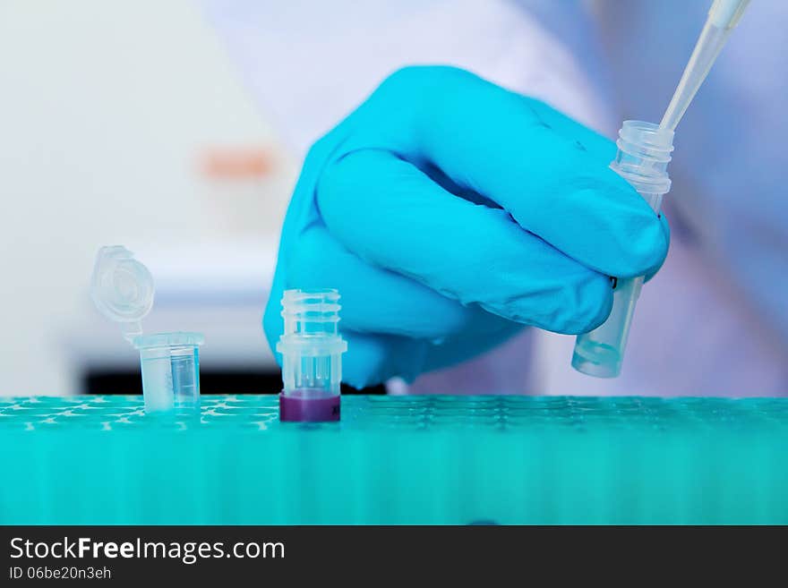 Pipette with drop of liquid in a science research lab