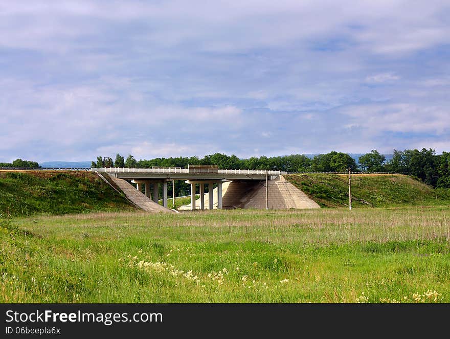 Bridge over a highway against a summer landscape with a meadow. Bridge over a highway against a summer landscape with a meadow