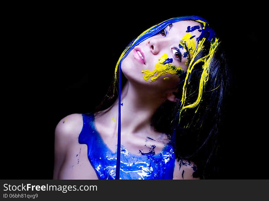 Beauty/fashion close up portrait of woman painted blue and yellow on black background