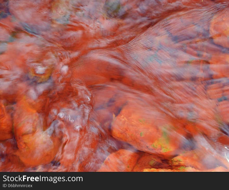 Playful ripples pink color ferrous water of a river. Playful ripples pink color ferrous water of a river