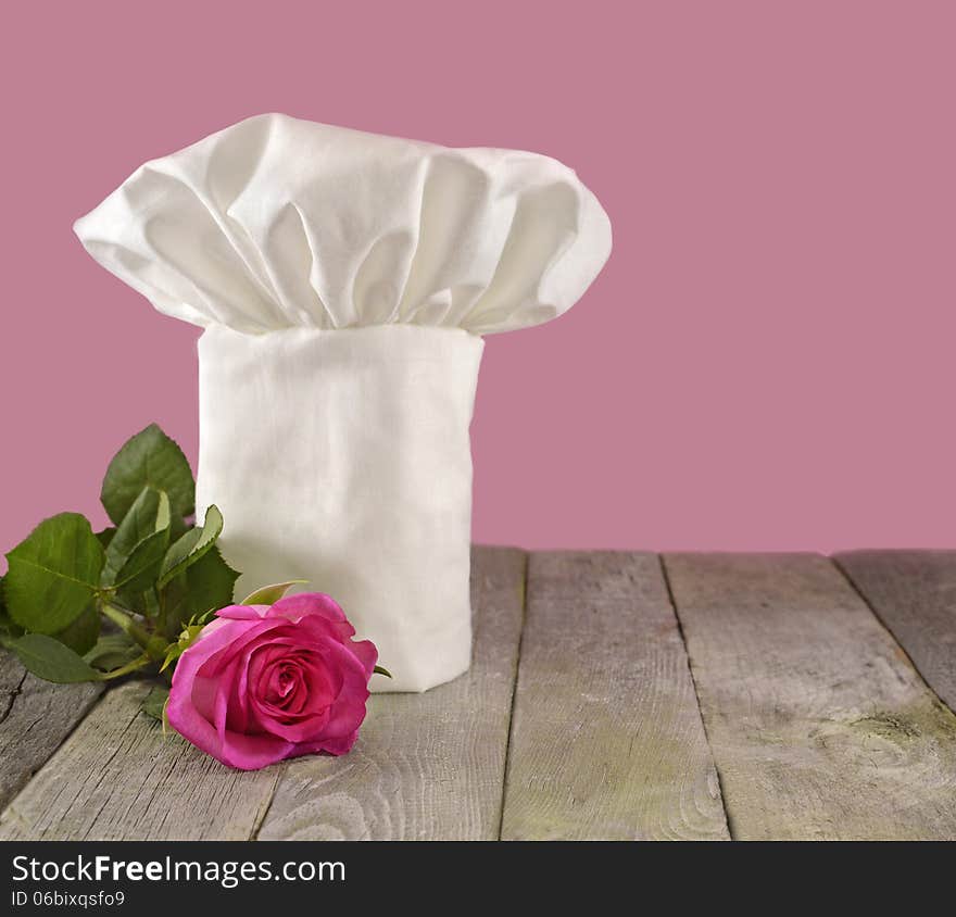 White chef's toque with pink rose isolated on pink. White chef's toque with pink rose isolated on pink