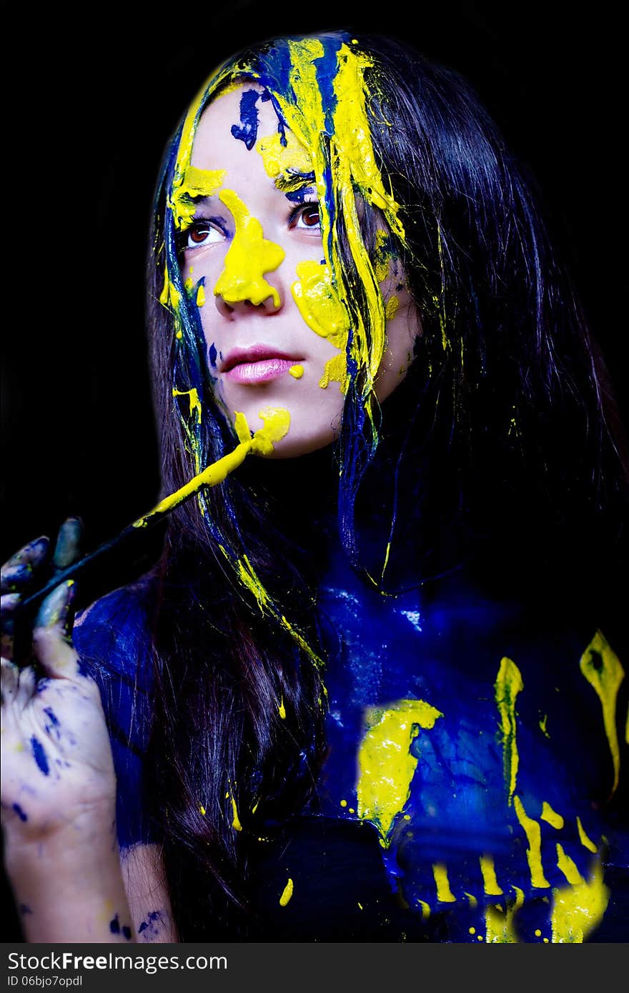 Beauty/fashion Close Up Portrait Of Woman Painted Blue And Yellow With Brushes And Paint  On Black Background