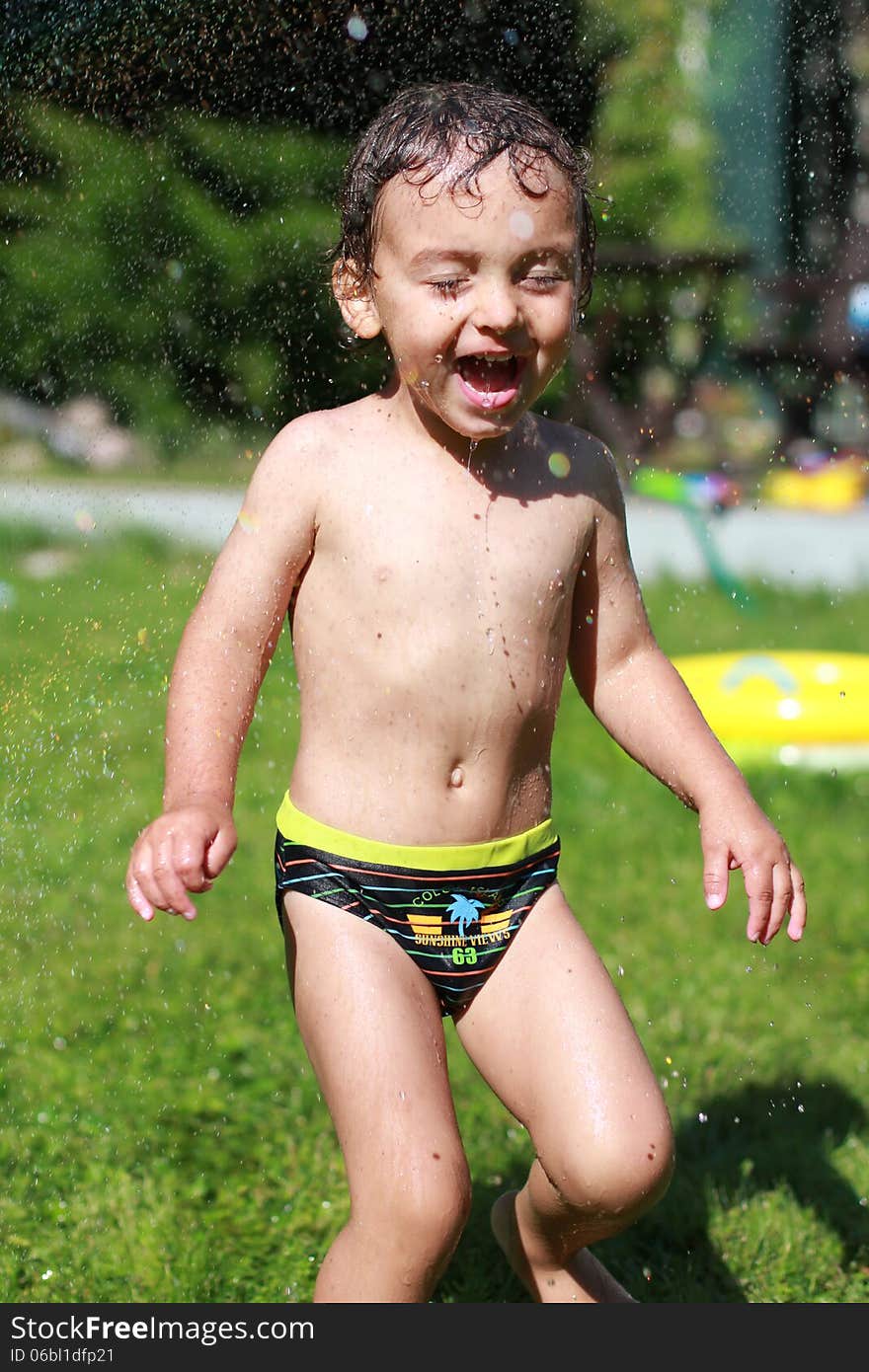 Little boy running in the garden, summer day, water droplets. Little boy running in the garden, summer day, water droplets