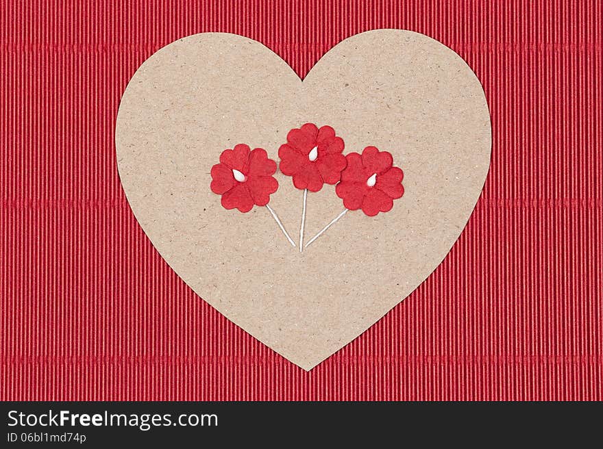 Cardboard heart with paper flowers on red goffer background.