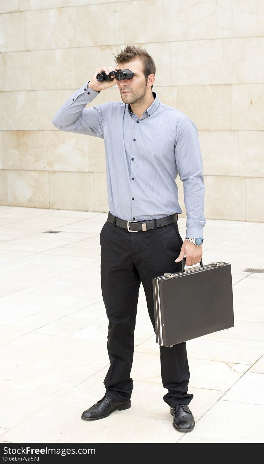 Businessman with briefcase looking through binoculars.