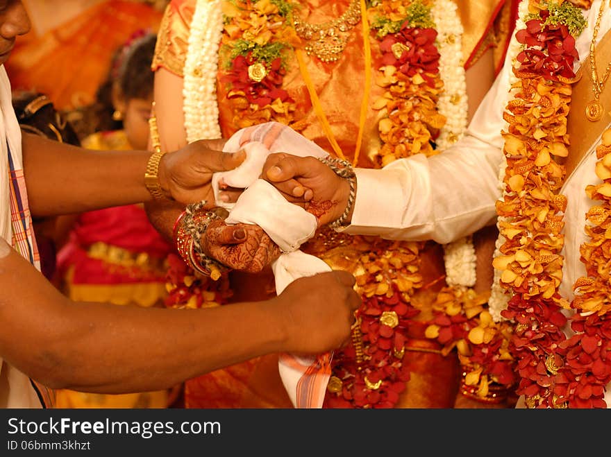 Cropped picture of a wedding couple holding their hands together to tie a knot with a cloth