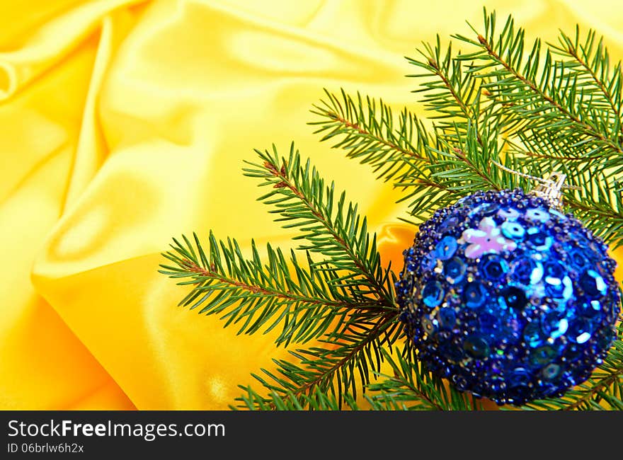 Christmas tree and ball on a gold silk background. Christmas tree and ball on a gold silk background