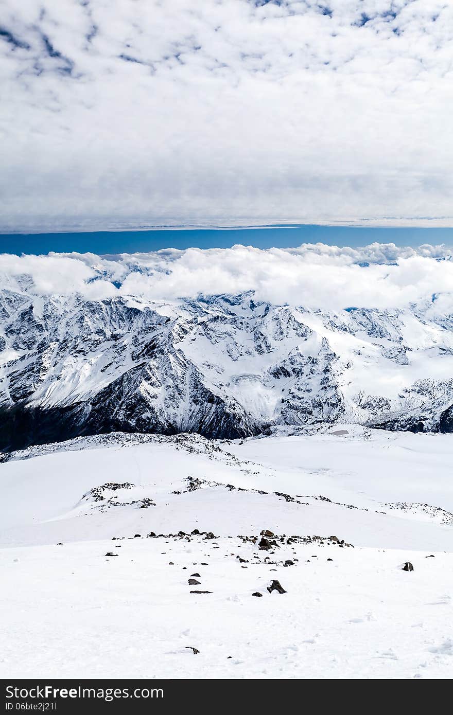 Mountain landscape in autumn or winter in Caucasus Mountains i Russia and Georgia. View from slopes of Mount Elbrus 5642m. Lot of white snow on rocky mountain ridge over blue sunny sky, Russia. Mountain landscape in autumn or winter in Caucasus Mountains i Russia and Georgia. View from slopes of Mount Elbrus 5642m. Lot of white snow on rocky mountain ridge over blue sunny sky, Russia.