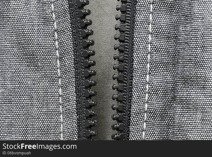 Fragment of open plastic zipper fastener of gray cotton jacket. Fragment of open plastic zipper fastener of gray cotton jacket