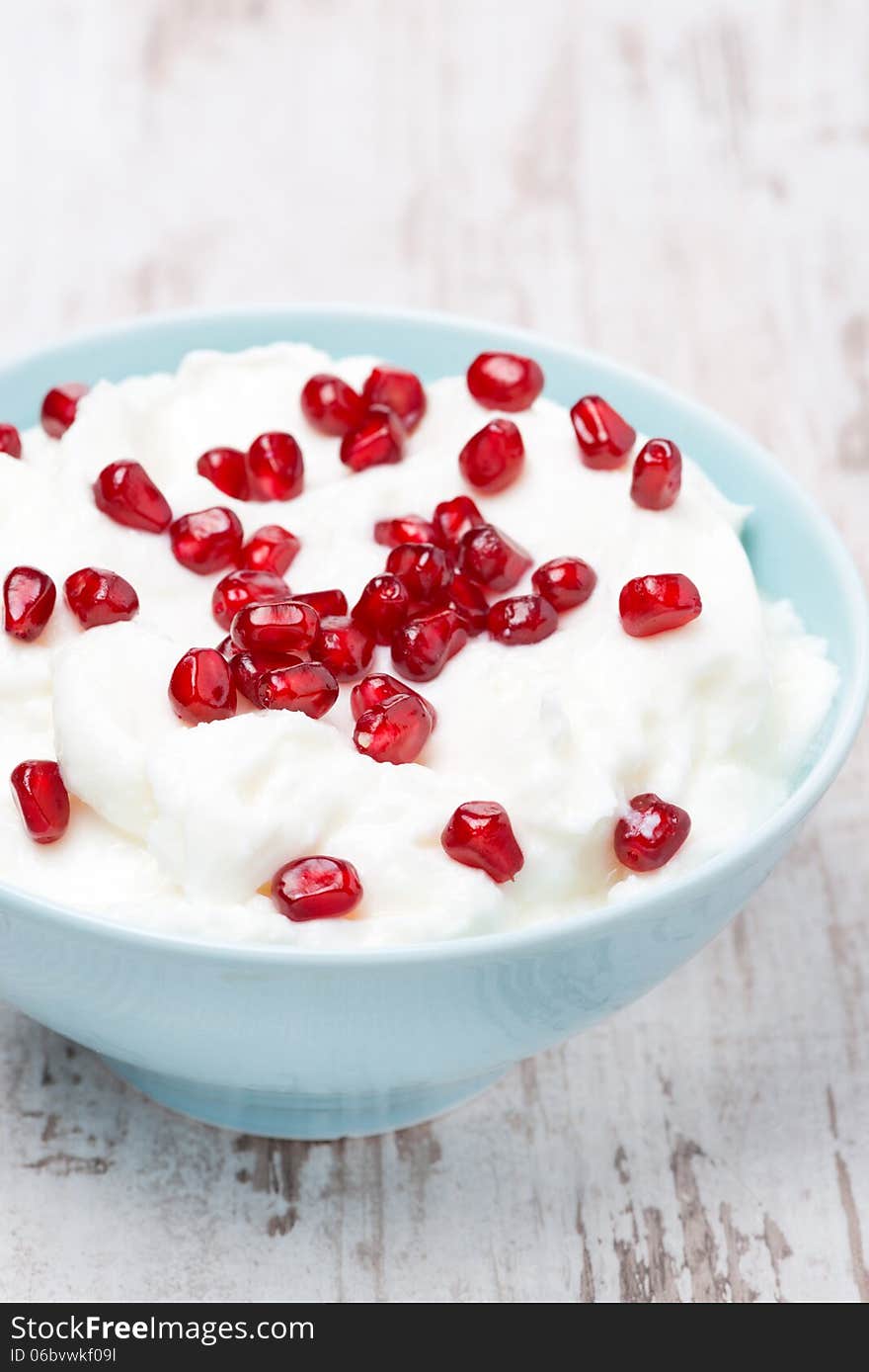 Homemade yogurt with pomegranate seeds in a bowl, vertical