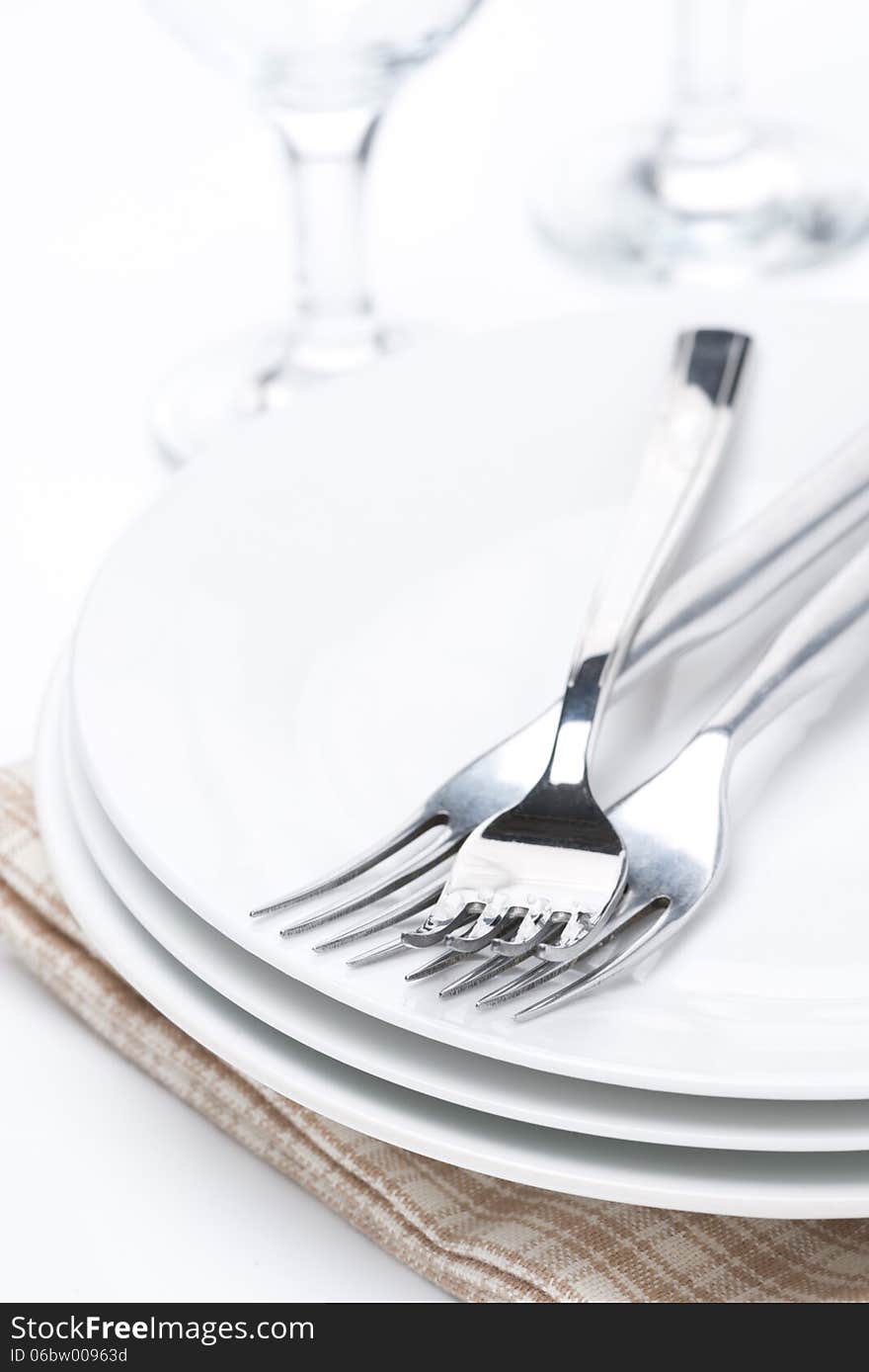 Tableware for dinner - plates, forks and glasses, selective focus, vertical. Tableware for dinner - plates, forks and glasses, selective focus, vertical