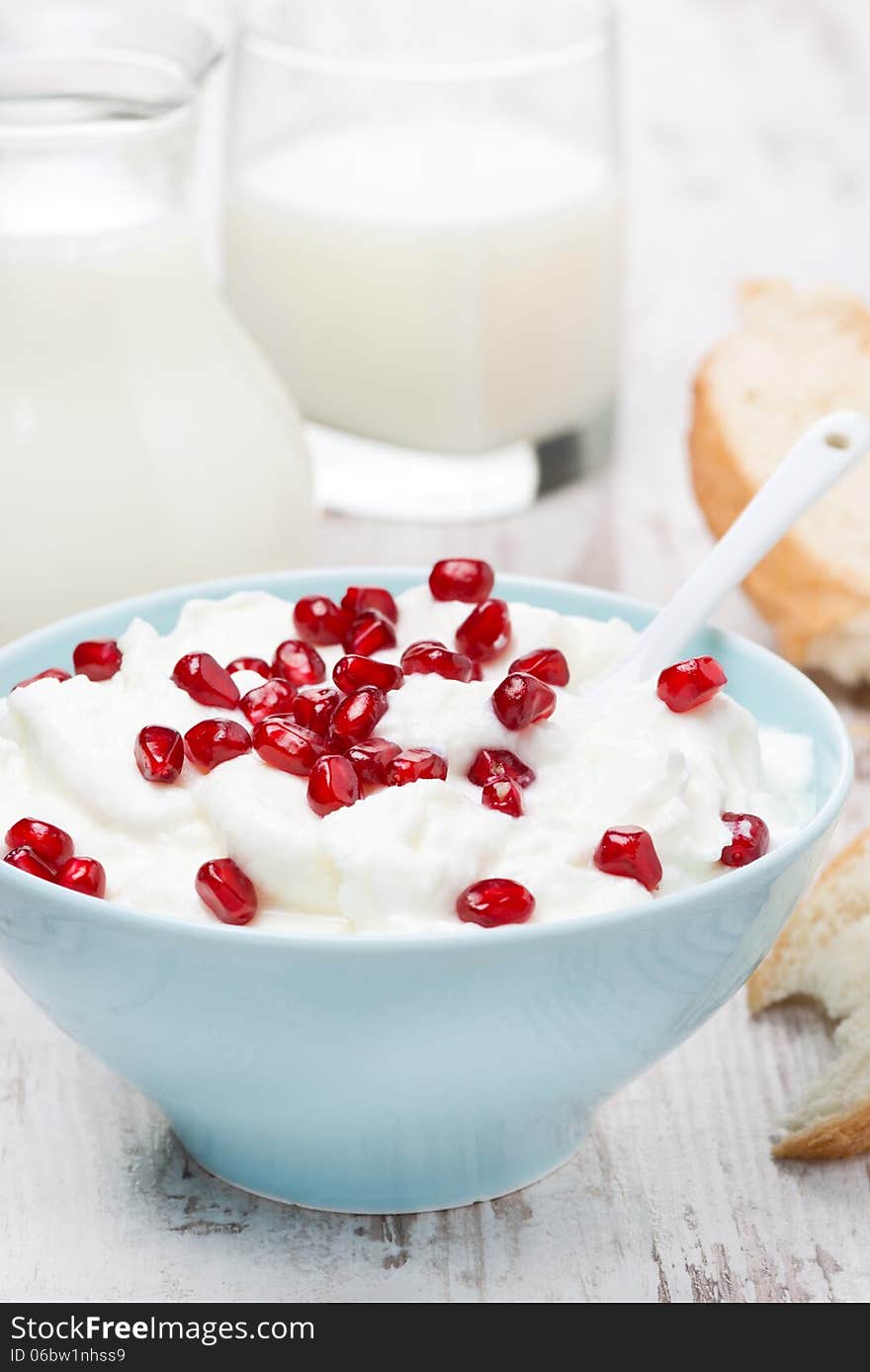 Fresh homemade yogurt with pomegranate, milk and bread for breakfast, vertical