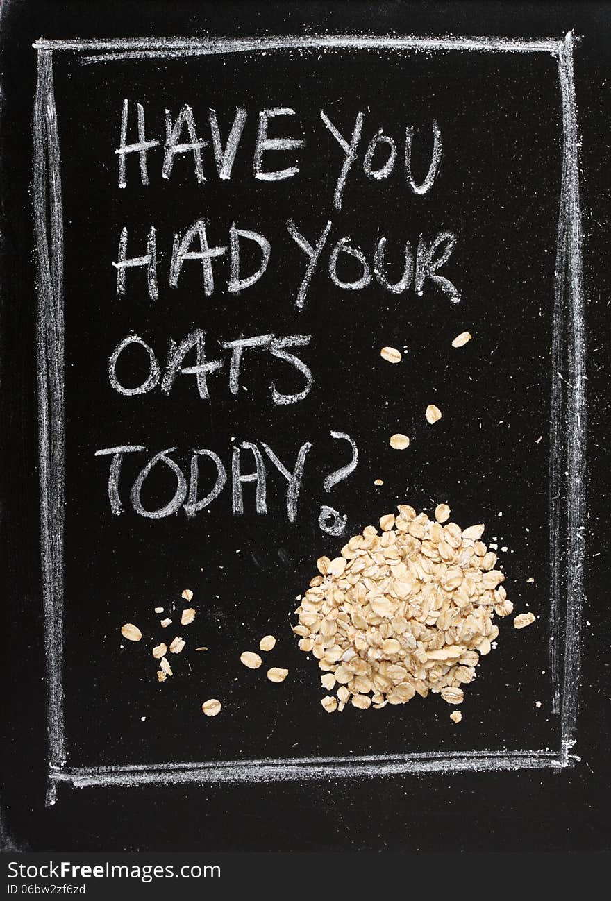 Have You Had Your Oats Today? Hand written on a used blackboard with a pile of porridge oats alongside as a concept for healthy eating.