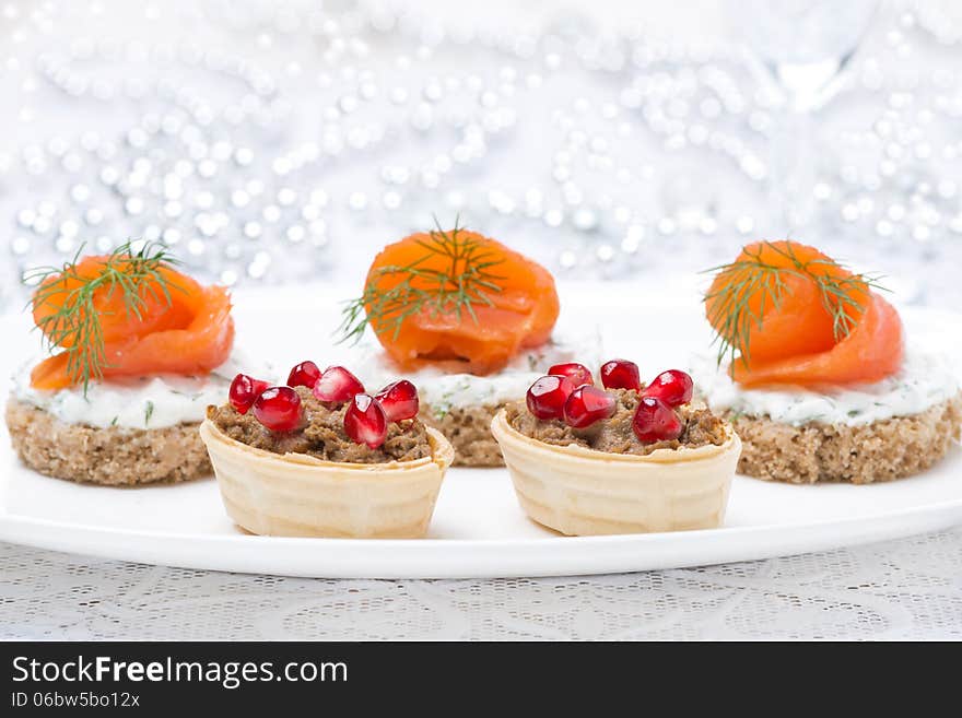 Holiday appetizers - canape with salmon and tartlet with liver pate for Christmas, selective focus, close-up. Holiday appetizers - canape with salmon and tartlet with liver pate for Christmas, selective focus, close-up