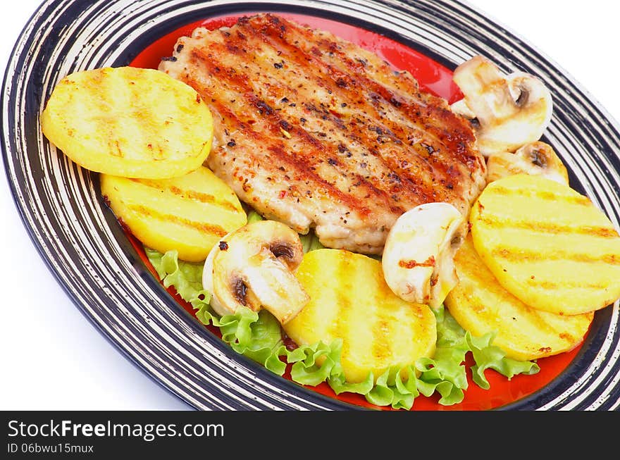 Roasted Turkey Steak Garnished with Grilled Sliced Potato, Portabello Mushrooms and Lettuce closeup on Striped Plate