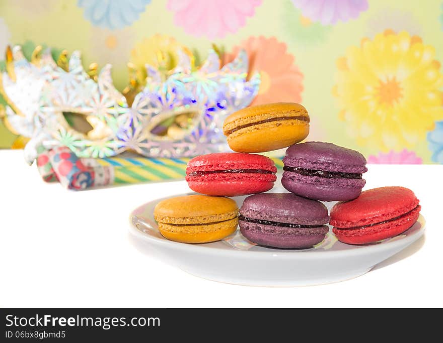 Sweet colorful macaron against festive masks and pipes