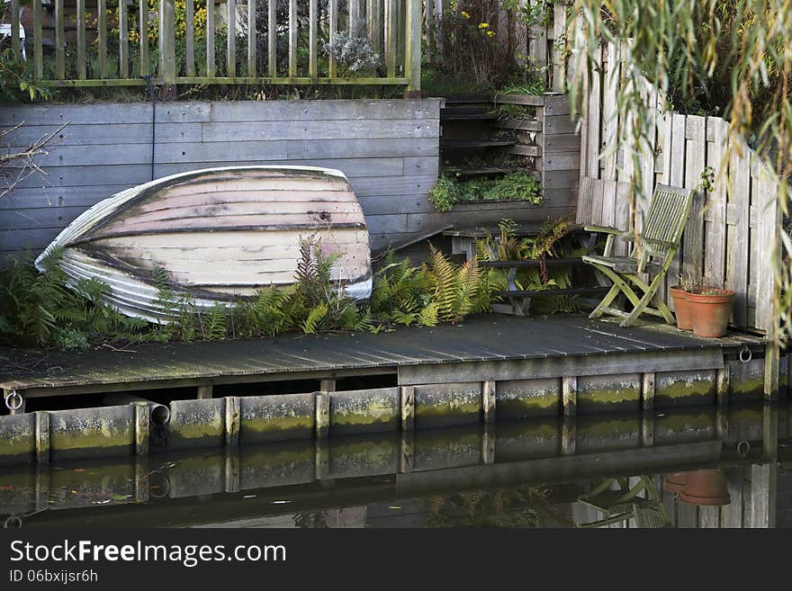 Boat resting on its side in the garden near the water. Boat resting on its side in the garden near the water