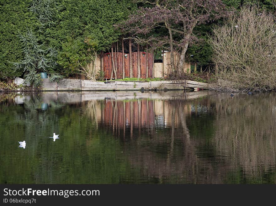 Wooden fence and reflections in the water of a lake. Wooden fence and reflections in the water of a lake