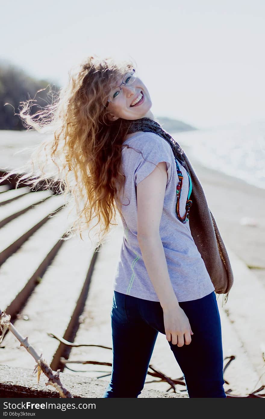 Happy woman with glasses and curly hair on bright sunny background