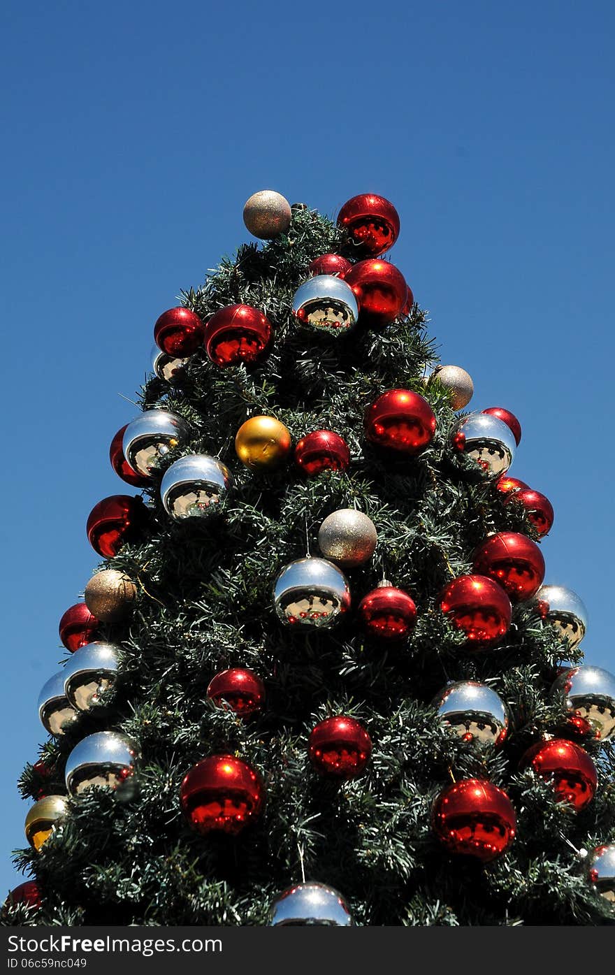 A Christmas tree decorated with red and silver and gold baubles glints under an African sun and blue summer sky. A Christmas tree decorated with red and silver and gold baubles glints under an African sun and blue summer sky.